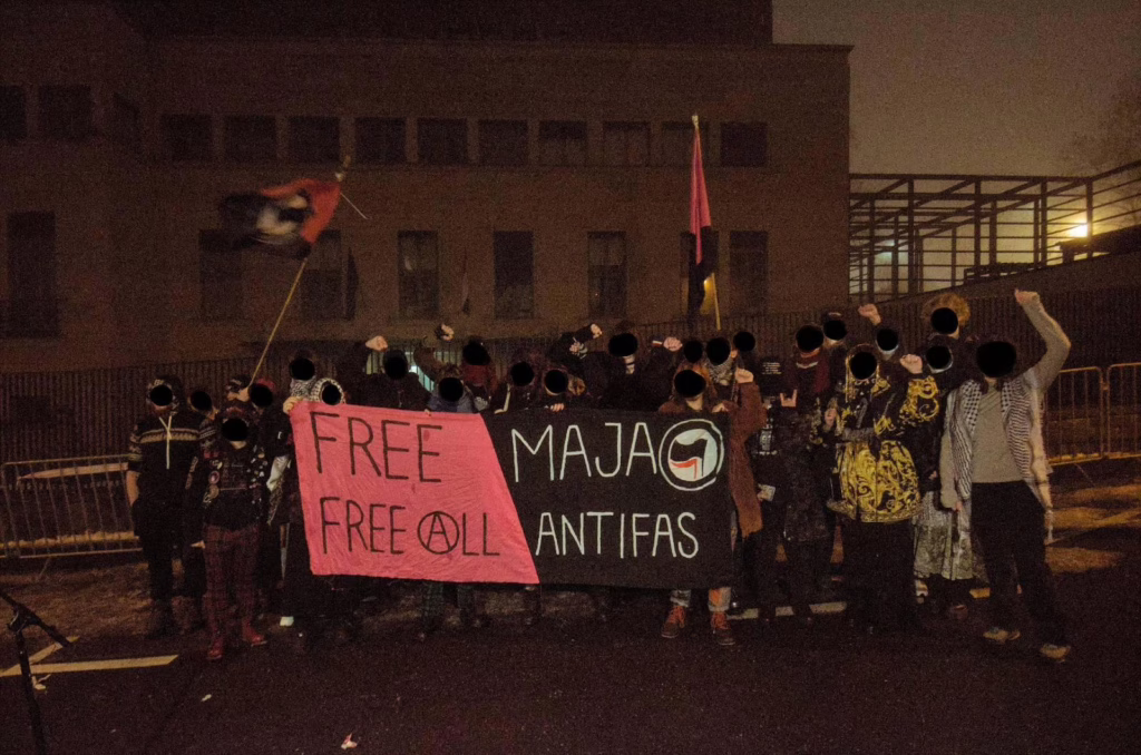 Crowd with a FREE MAJA, FREE ALL ANTIFAS banner and queer anarchist flags.